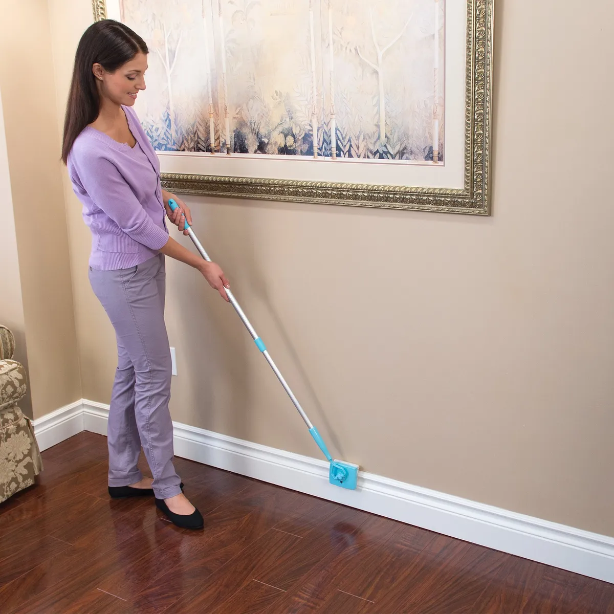 Cleaning a white baseboard with Baseboard Buddy while standing